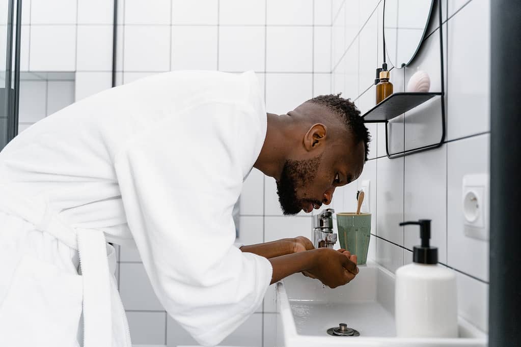 a man washing his face on the bathroom sink