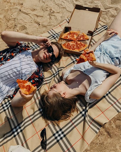 couple laying down and eating pizza